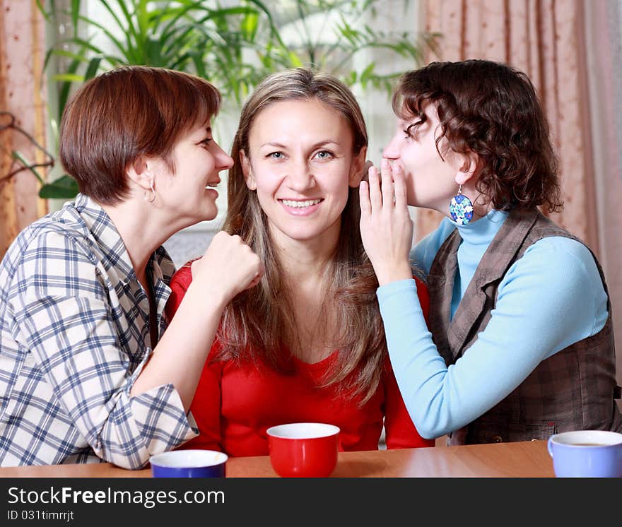 Two women share secrets with a friend at home