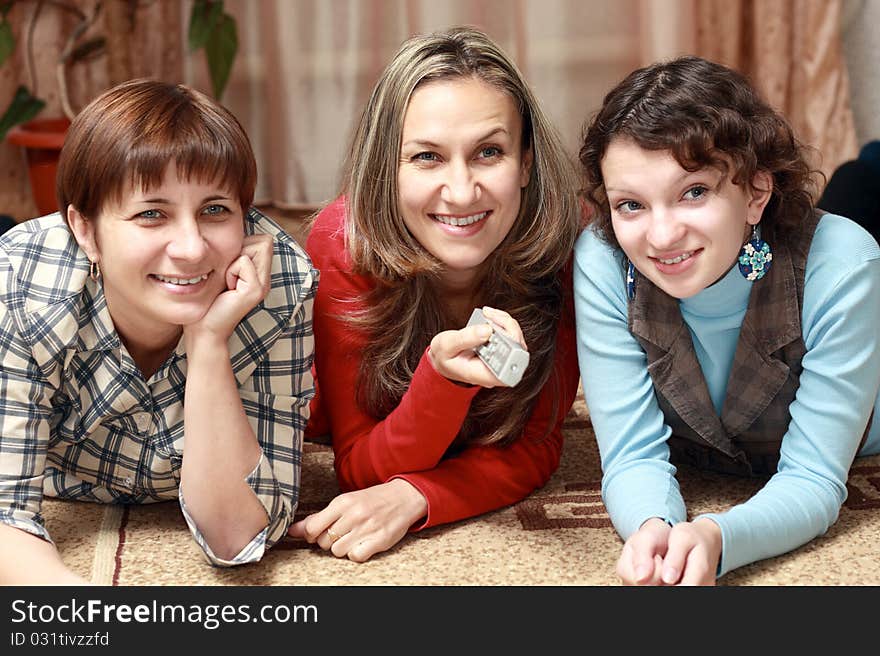 Three women watching television at home