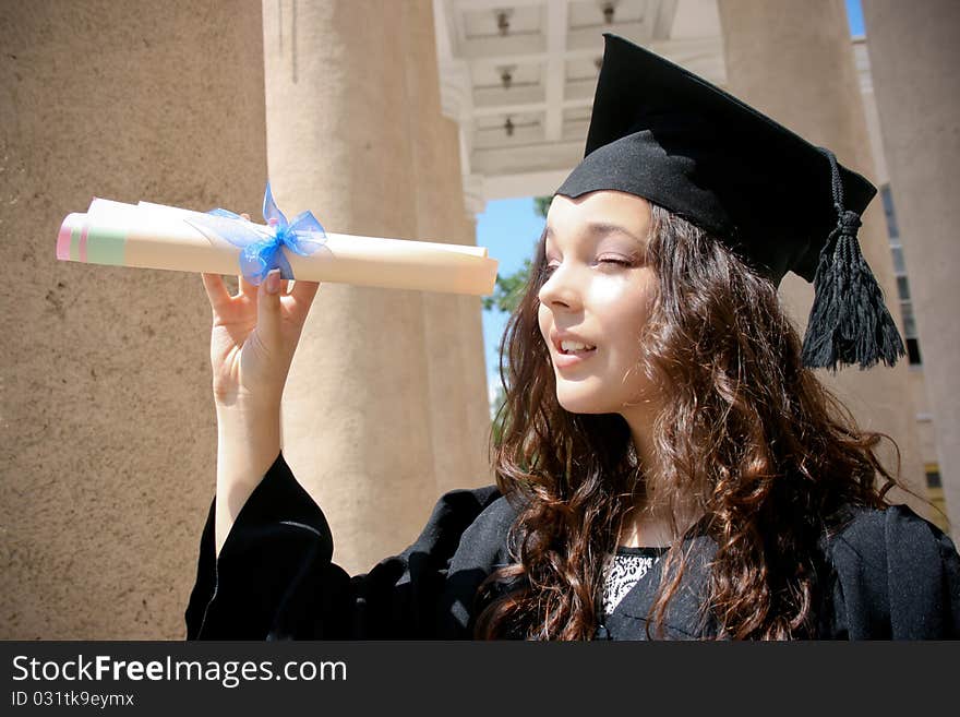 Young student in gown near the university with diploma. Young student in gown near the university with diploma