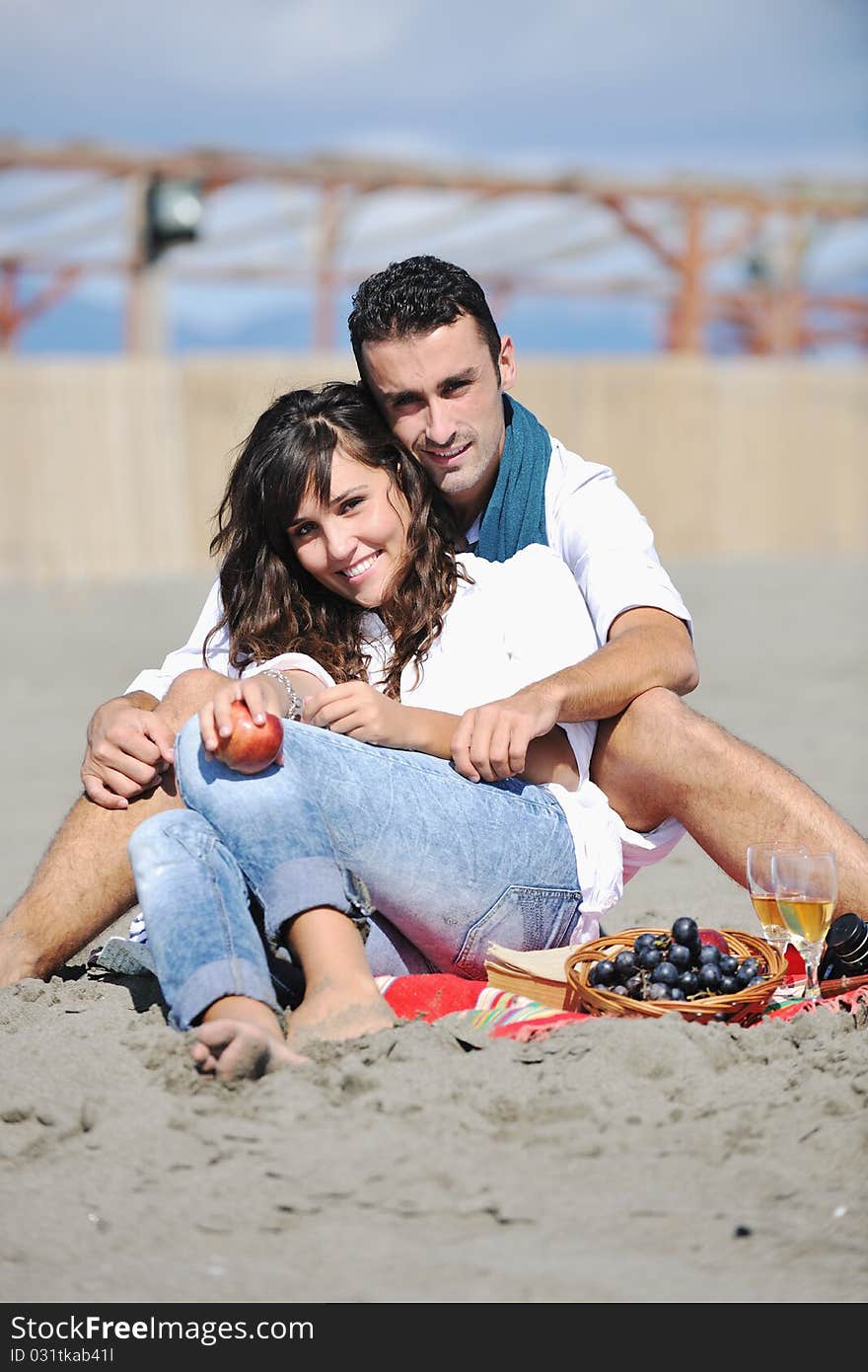 Happy young couple enjoying picnic on the beach and have good time on summer vacations. Happy young couple enjoying picnic on the beach and have good time on summer vacations