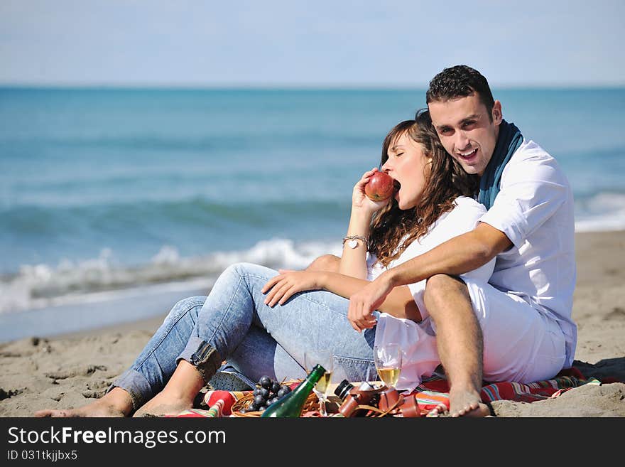 Happy young couple enjoying picnic on the beach and have good time on summer vacations. Happy young couple enjoying picnic on the beach and have good time on summer vacations