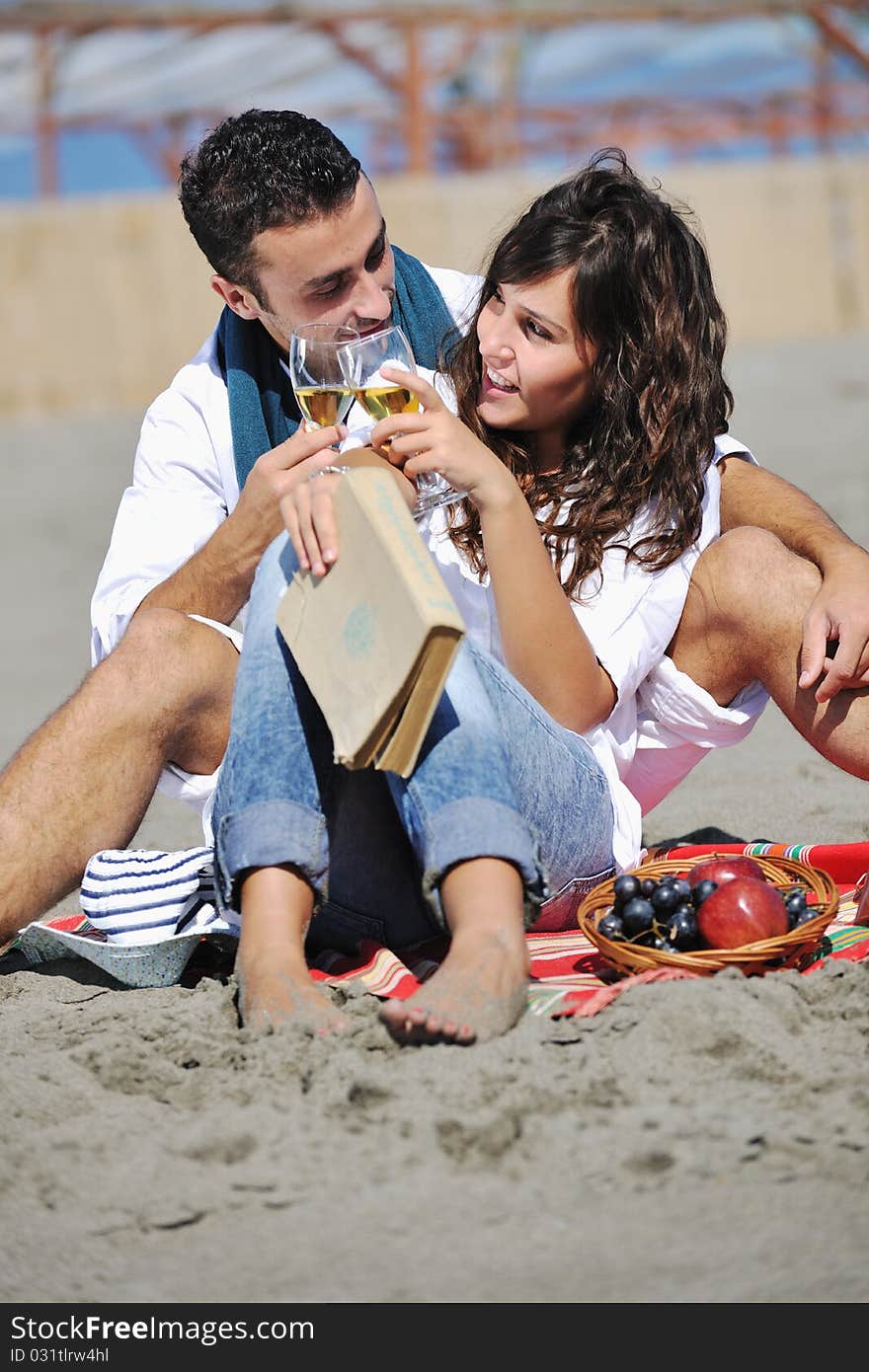 Happy young couple enjoying picnic on the beach and have good time on summer vacations. Happy young couple enjoying picnic on the beach and have good time on summer vacations