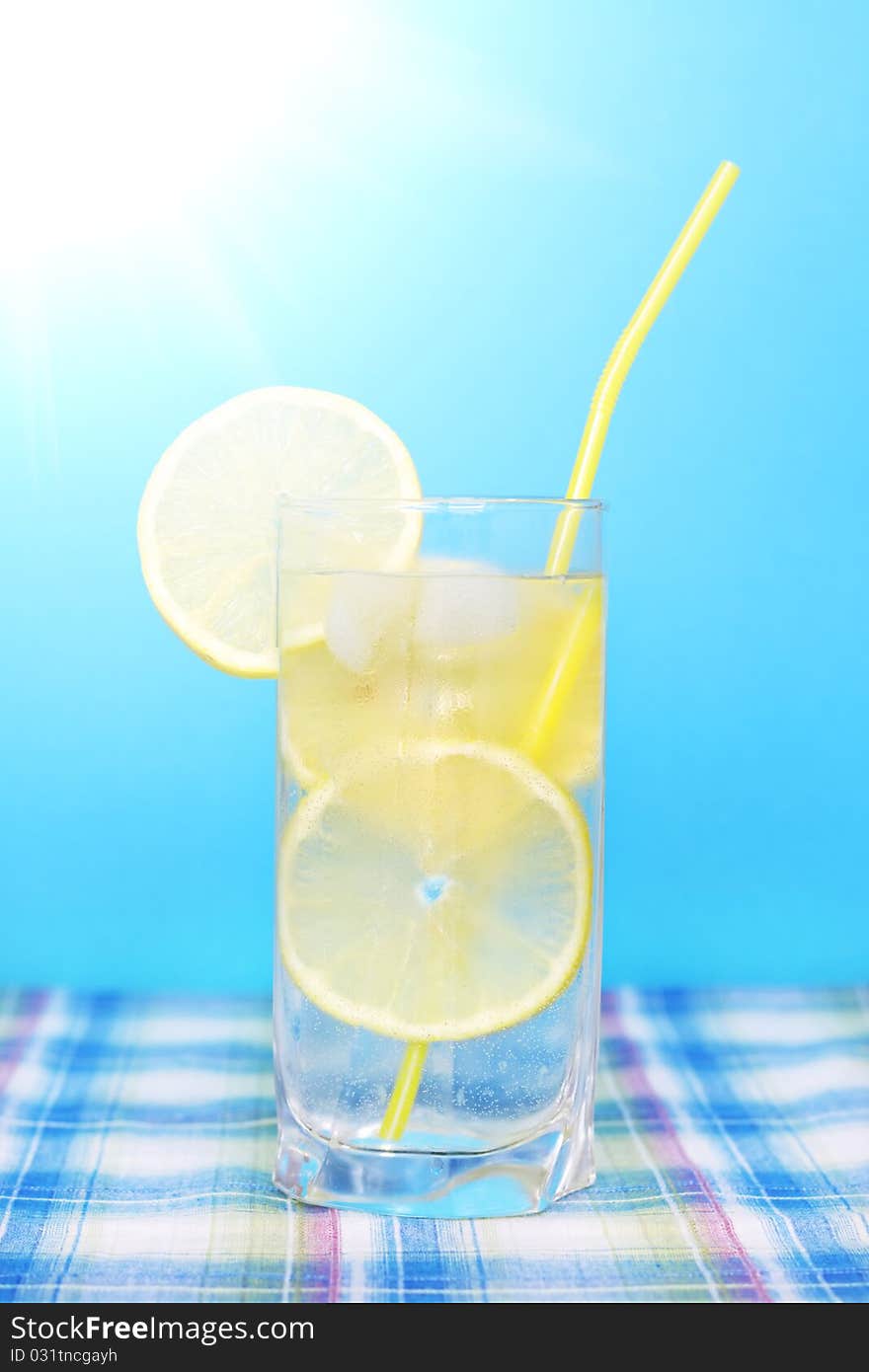 Glass of water with lemon on a blue background