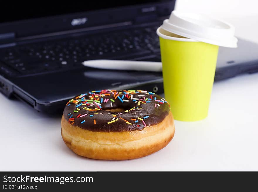 Paper coffee cup, donut and notebook out of focus. Paper coffee cup, donut and notebook out of focus