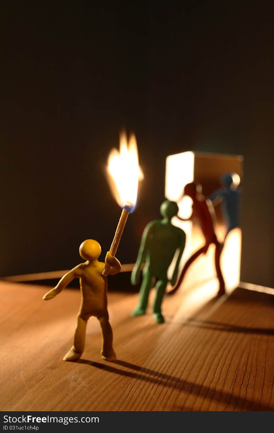 Few plasticine men with lighting match entering to dark room. Conceptual composition with open door made from paper