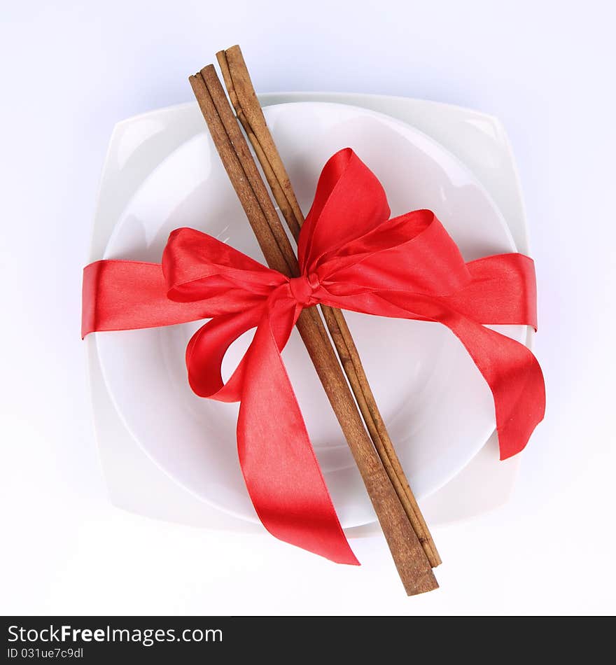 Plate with christmas decoration with cinnamon sticks and ribbon on white background. Plate with christmas decoration with cinnamon sticks and ribbon on white background