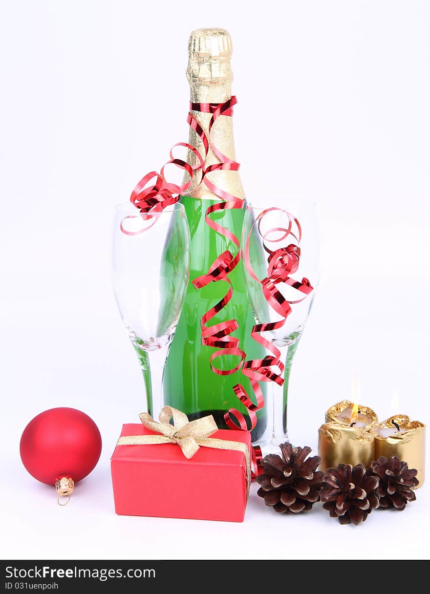 Christmas and New Year's setting - a bottle of champagne, glasses, candles, a gift, and cones on white background