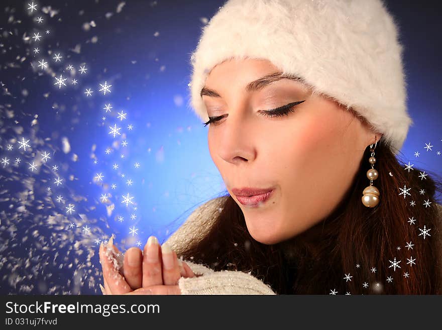 Cute young woman blows snowflakes. Cute young woman blows snowflakes