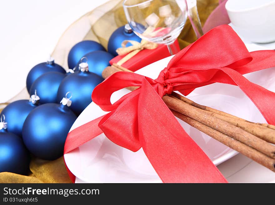 Christmas or New Year's setting - a plate decorated with cinnamon sticks and ribbon and christmas balls in close up