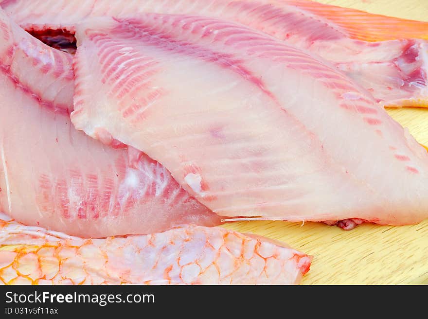 Red tilapia on wood chopping block .