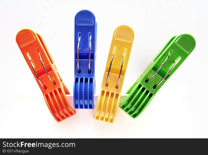 Four colorful clothes pegs over white background