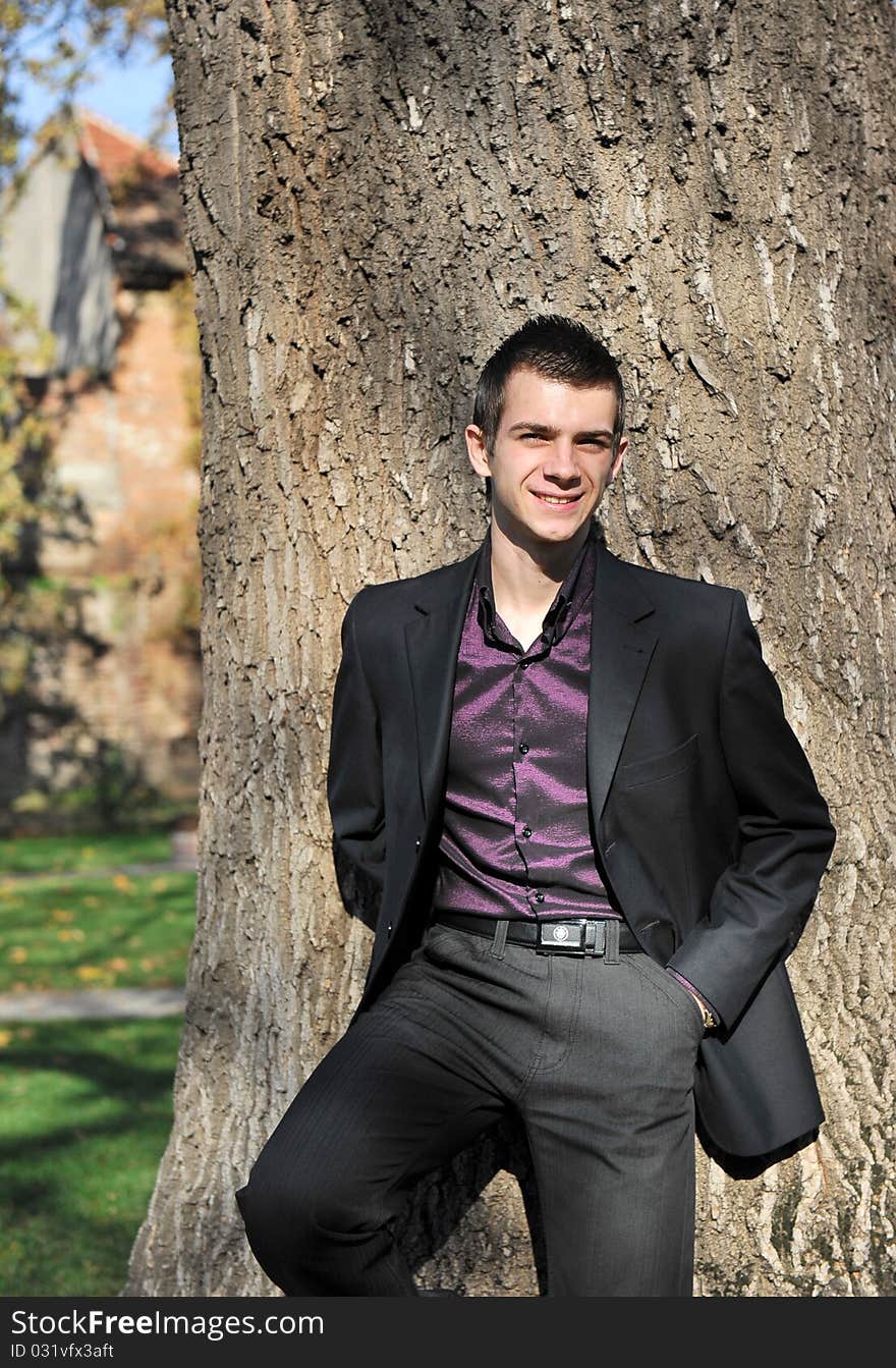 Portrait of happy attractive young man leaning on a tree. Portrait of happy attractive young man leaning on a tree