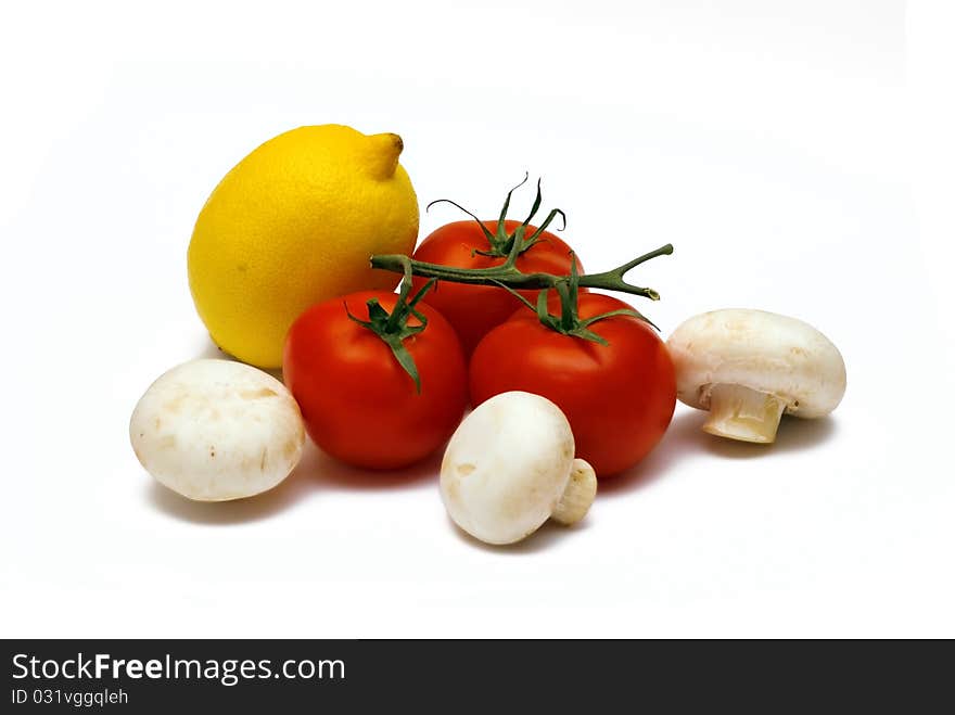 The yellow ripe juicy lemon, red tomato and mushrooms lies on a white background. The yellow ripe juicy lemon, red tomato and mushrooms lies on a white background