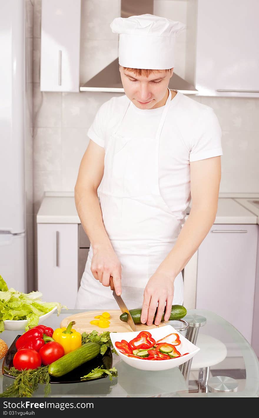 Happy young cook making salad in the kitchen. Happy young cook making salad in the kitchen