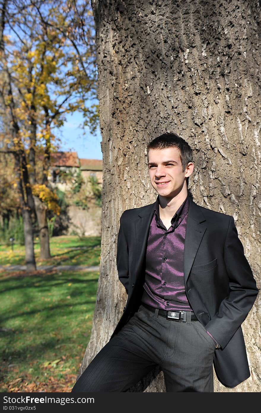 Portrait of happy attractive young man leaning on a tree. Portrait of happy attractive young man leaning on a tree