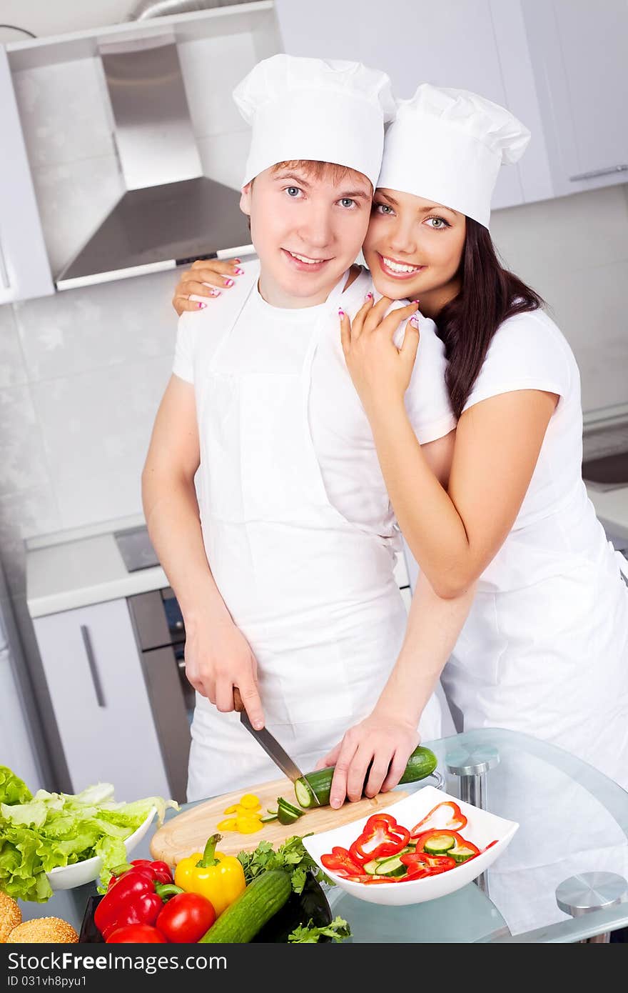 Two happy young cooks making salad in the kitchen. Two happy young cooks making salad in the kitchen