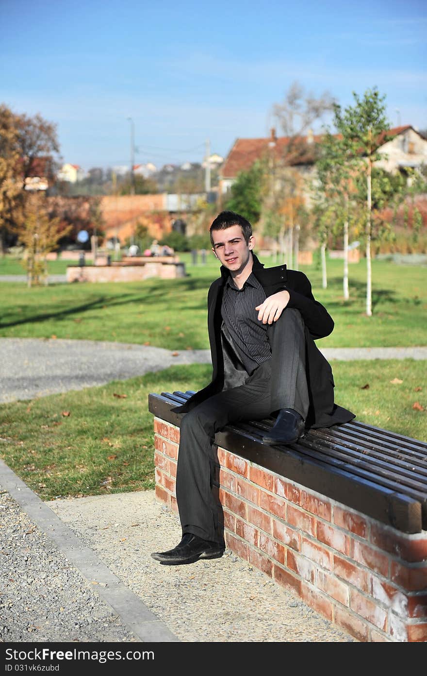 Portrait of happy attractive young man sitting on a bench