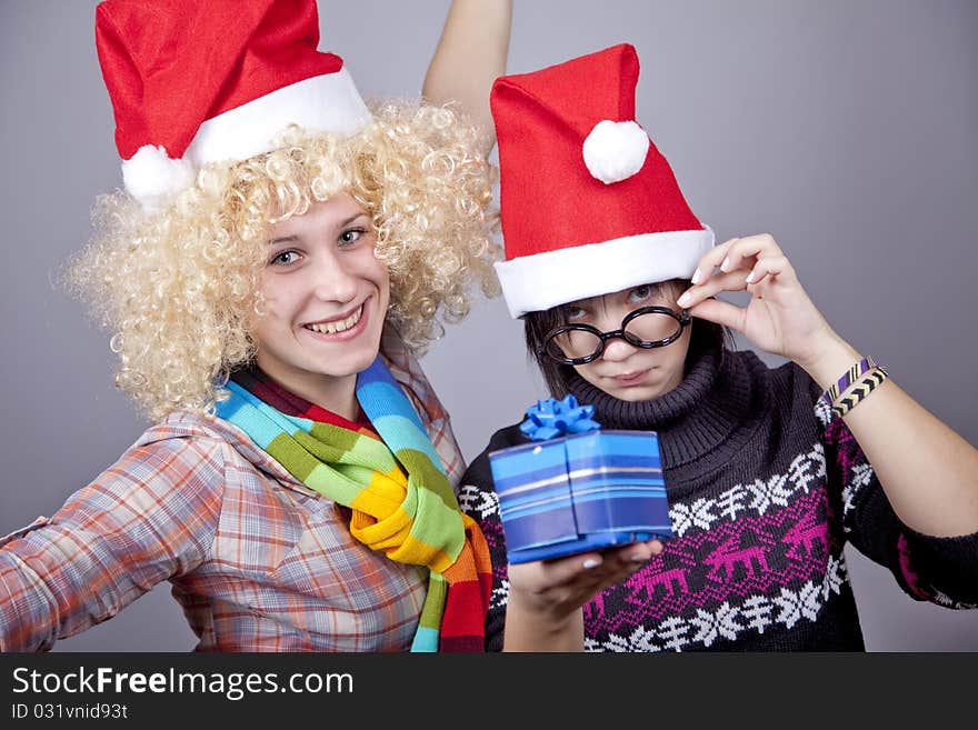 Two beautiful girls with gifts in christmas hats