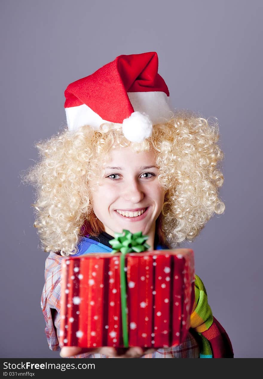 Girl in blonde wig and christmas hat show gift. Studio shot.