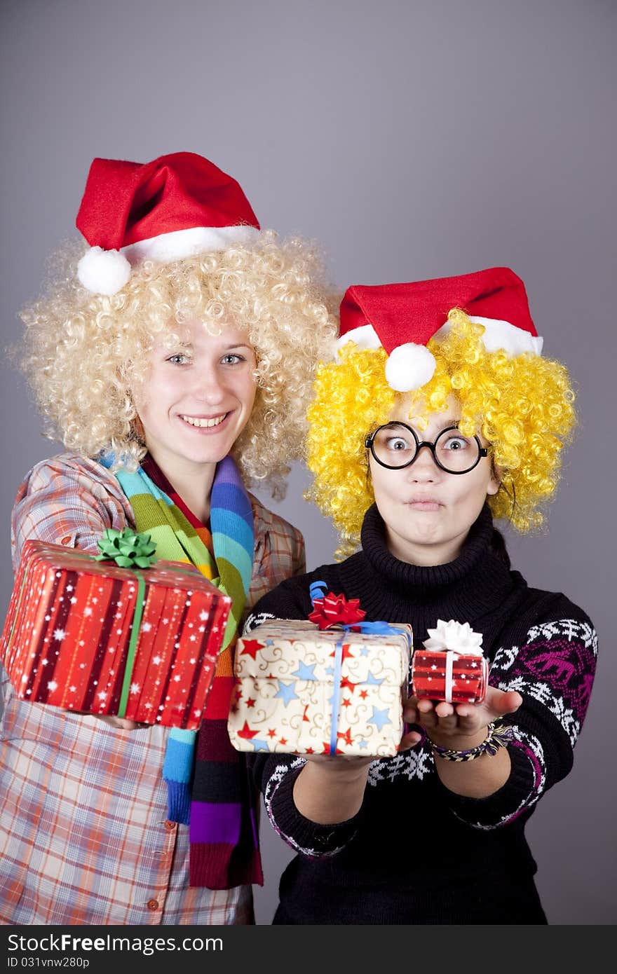 Two beautiful girls with gifts in christmas hats