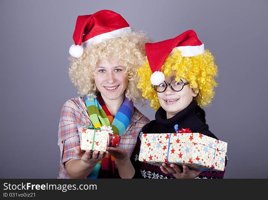 Two beautiful girls with gifts in christmas hats