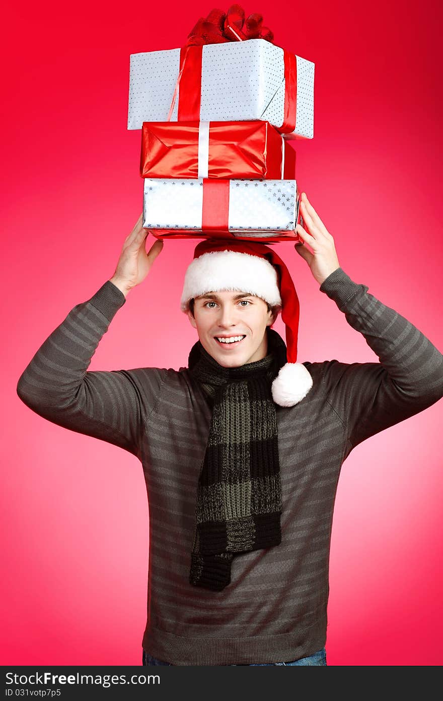 Portrait of a handsome young man in Santa Claus hat holding presents. Christmas. Portrait of a handsome young man in Santa Claus hat holding presents. Christmas.