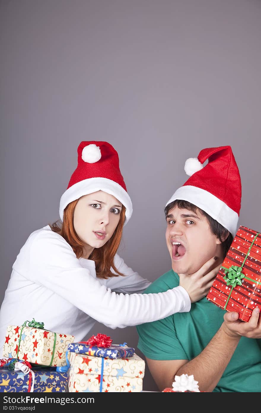 Girl strangling her boyfriend for a christmas gift. Studio shot.