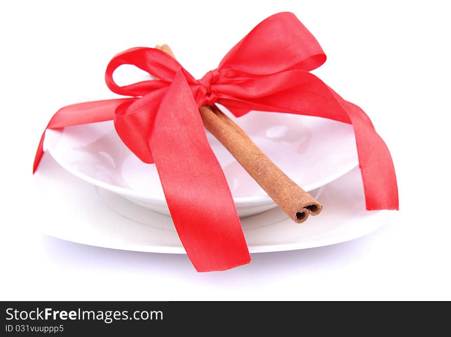 Christmas tableware-a plate decorated with cinnamon sticks and ribbon on white background