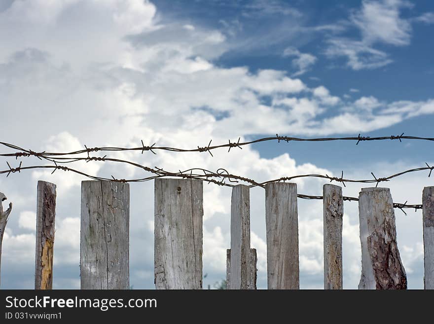 Barbed wire are stretched across top of wooden fence