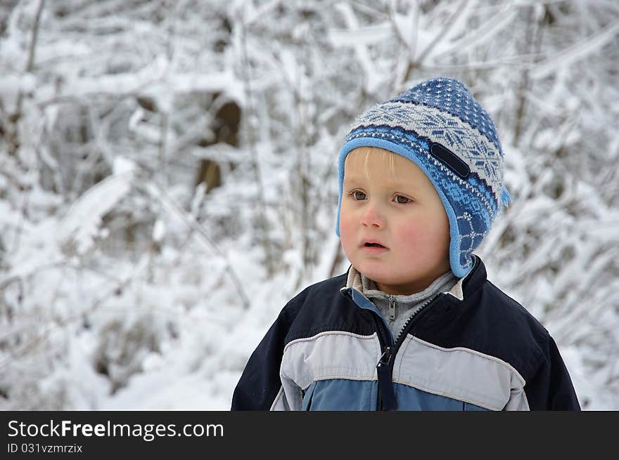 Young boy standing in a snowy scenery having nordic style hat on the head. Young boy standing in a snowy scenery having nordic style hat on the head