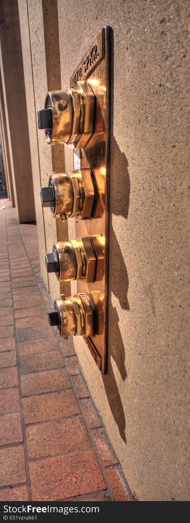 Plate with four brass fire taps on the wall of city building