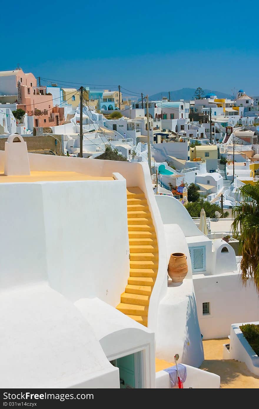 Landscape of city Fira with traditional houses on island of Santorini, Greece. Big yellow staircase in center of white building. Landscape of city Fira with traditional houses on island of Santorini, Greece. Big yellow staircase in center of white building.