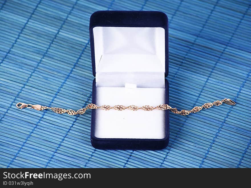 Blue jewerly box with gold bracelet on blue background