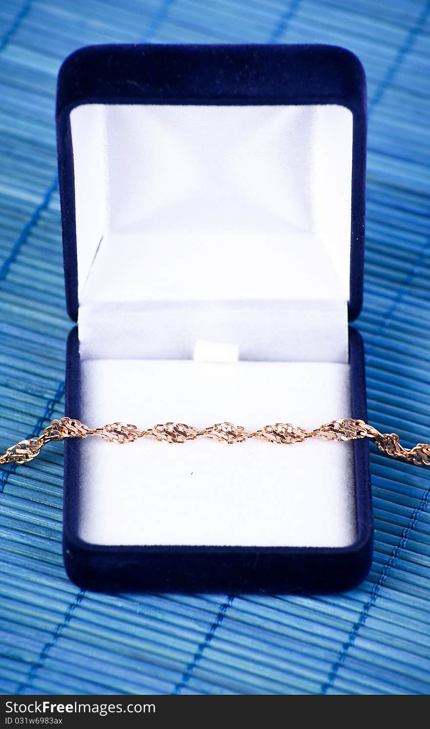 Blue jewerly box with gold bracelet on blue background