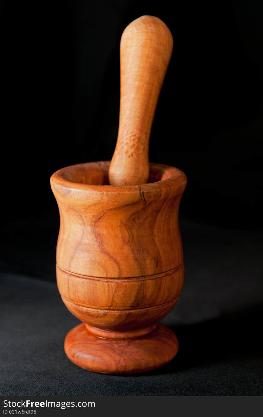 Wooden mortar and a pestle isolated on a black background. Wooden mortar and a pestle isolated on a black background.