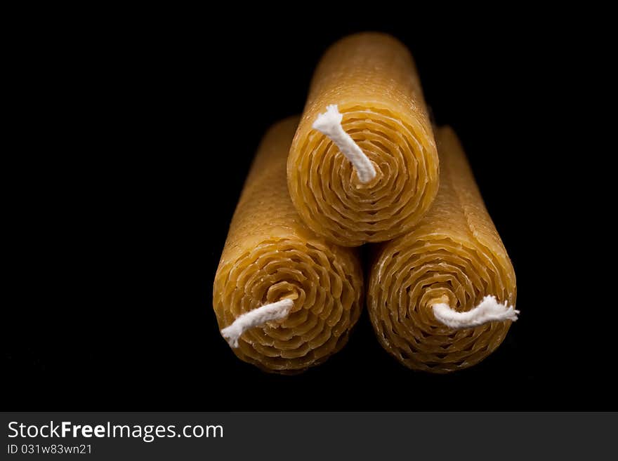 Three beeswax candles, end-on view, isolated on black with fading light