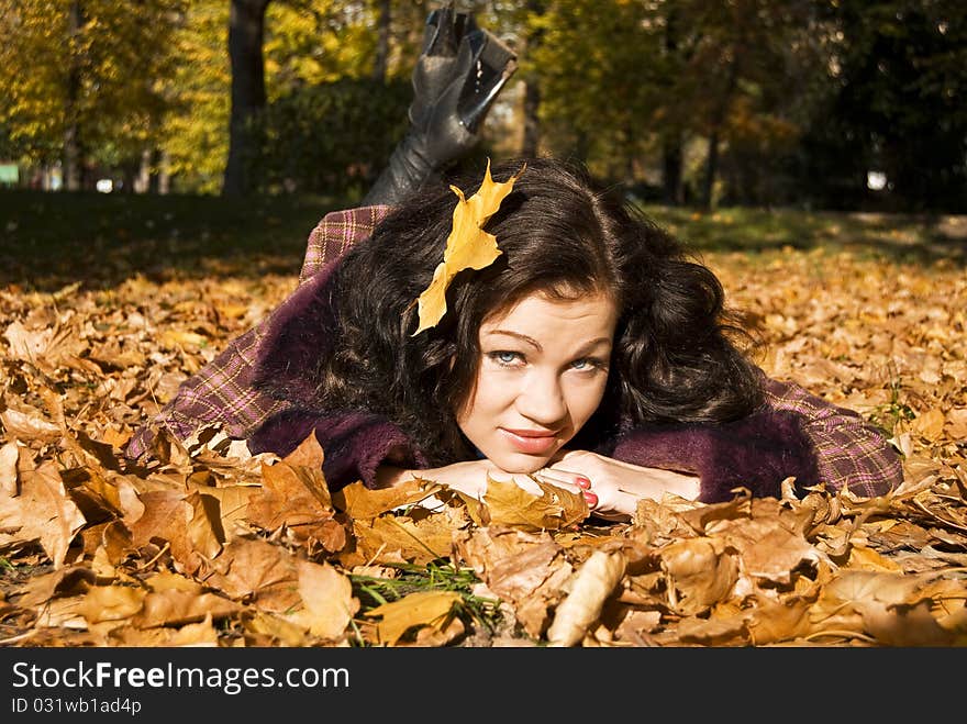 Pretty girl lays on the fallen leaves