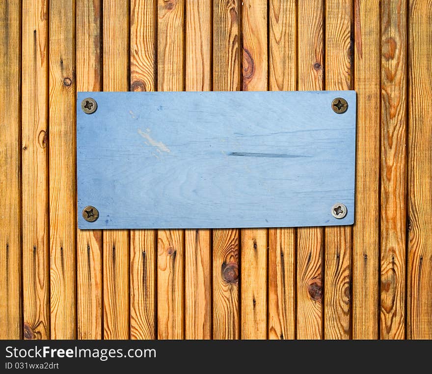 Empty plywood sign bolted to a wooden wall