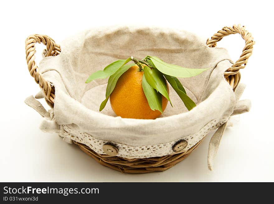 Tangerine with leaf in the basket with material