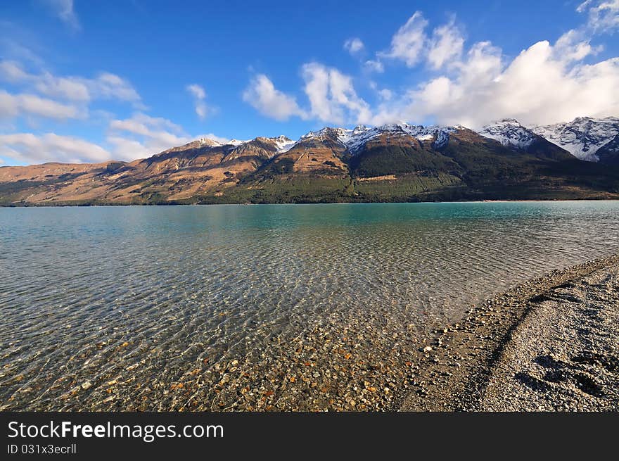 Volcanic snow-capped mountains reach toward the sky out of a crystal clear lake. Volcanic snow-capped mountains reach toward the sky out of a crystal clear lake.