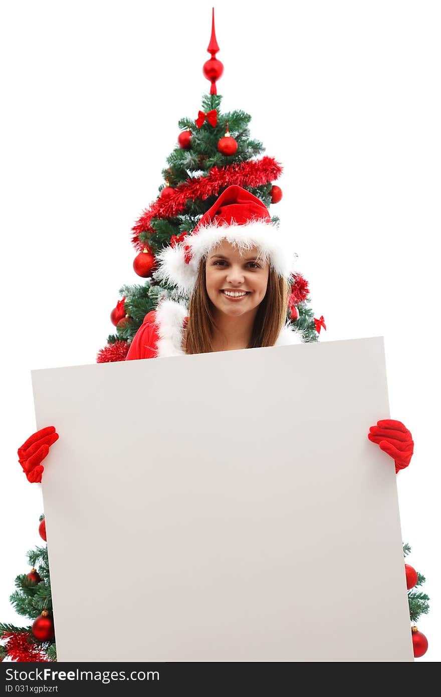 Attractive woman in santa clothes holding an empty board before the Christmas tree. Attractive woman in santa clothes holding an empty board before the Christmas tree