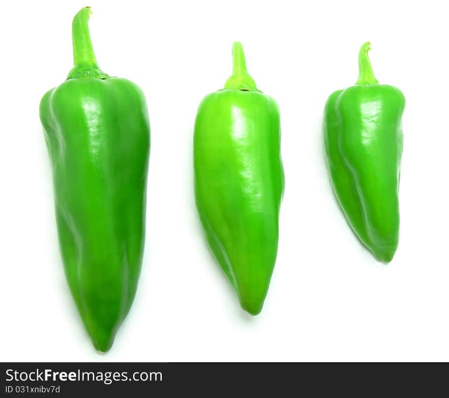 Three different sized green peppers on a white background.