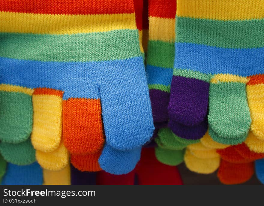 Close up of knitted striped winter gloves in bright colors