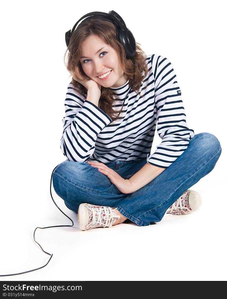 A teenager girl listening music in headphones on white background. A teenager girl listening music in headphones on white background