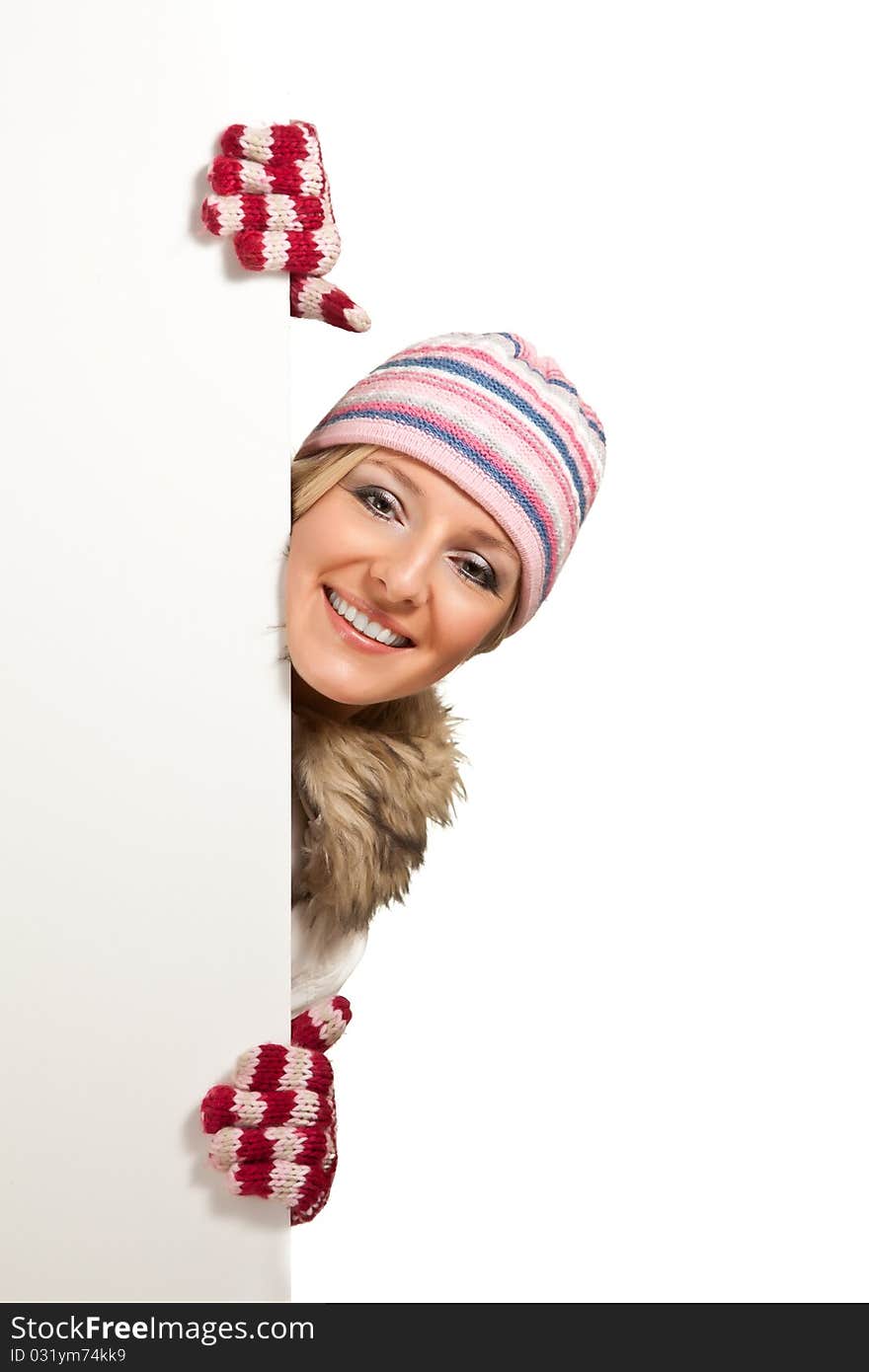 Woman in colorful hat and gloves peeping from behind whiteboard isolated on white. Woman in colorful hat and gloves peeping from behind whiteboard isolated on white