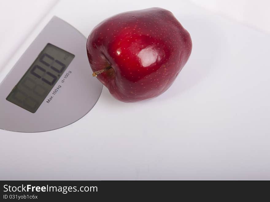 White electronic body weighing scales and a red apple.