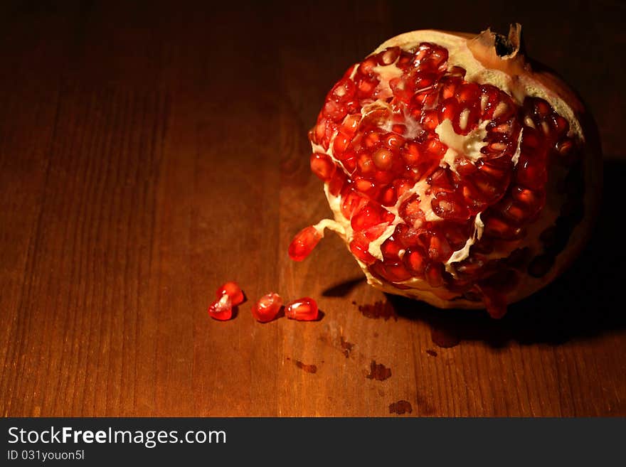 Fresh pomegranate lying on dark wooden background with lighting effect. Fresh pomegranate lying on dark wooden background with lighting effect