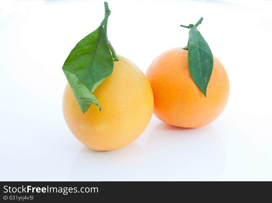 A pair of tarocco precoce oranges with leaves against a white background