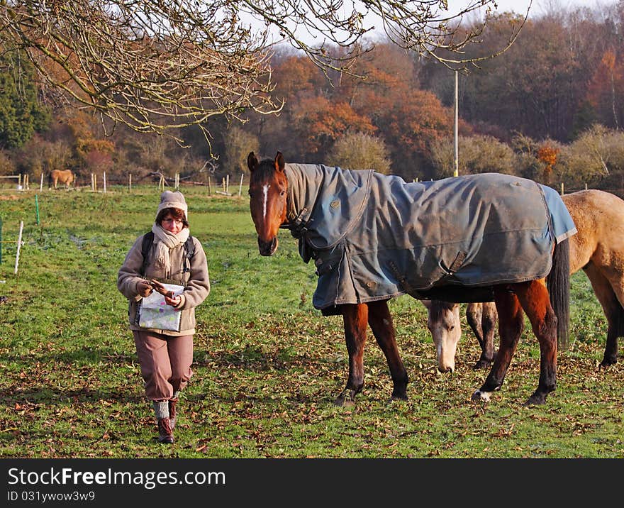 Female Hiking through a field with horses