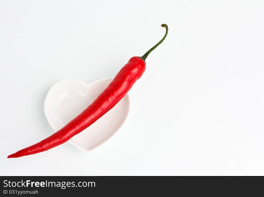 Red hot chili pepper on a heart shape saucer